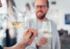 man in white sweater holding clear wine glass